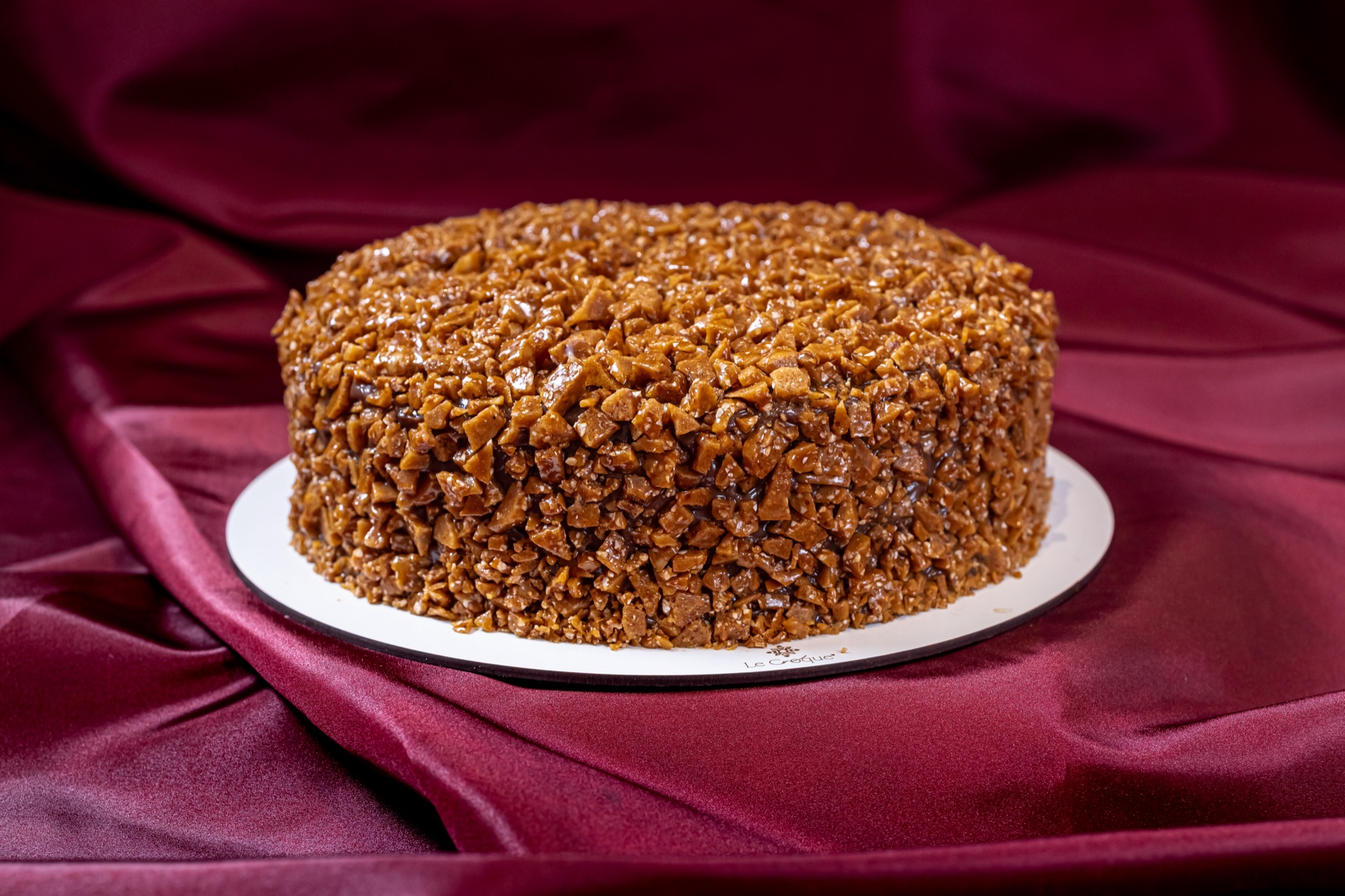 Bolo de chocolate Le Croque coberto de crocante sobre cetim vinho